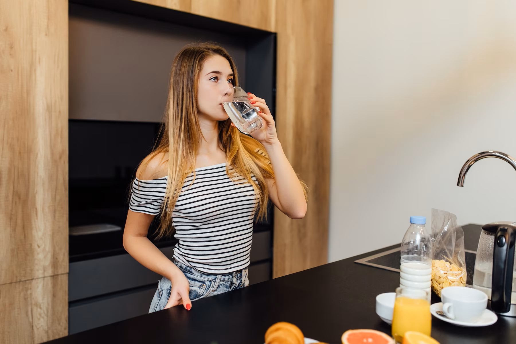 beautiful-young-blonde-woman-drinking-water-in-kitchen-with-healthy-food-on-table_496169-1128.jpg