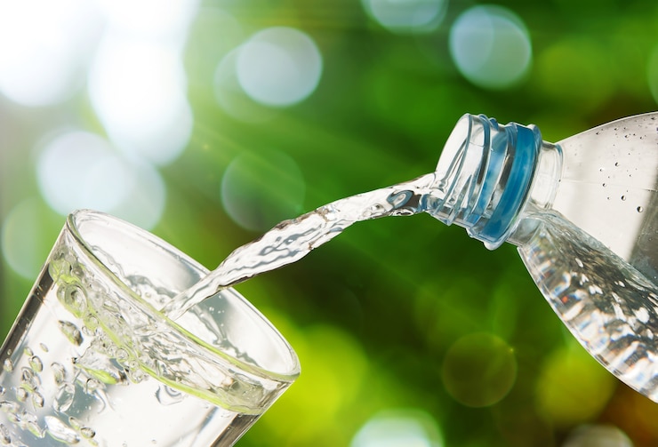 drinking-water-is-poured-from-a-bottle-into-a-glass-on-green-bokeh-background_53089-115.jpg